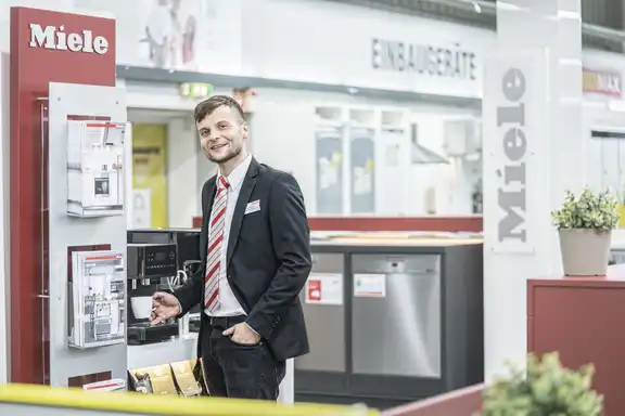 Mann in schwarzem Anzug mit einer Kaffeetasse in der Hand bei Miele