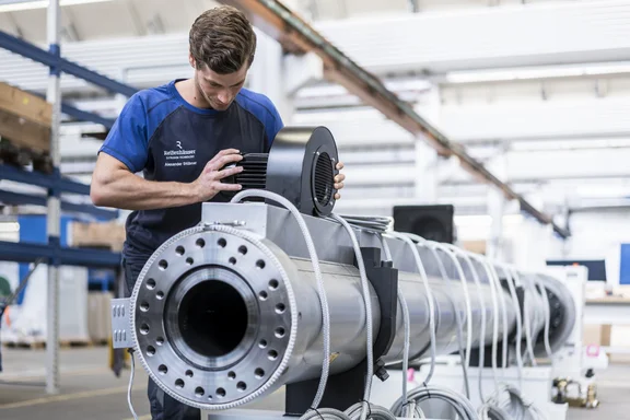 Mann, der an einer langen röhrenartigen Maschine arbeitet