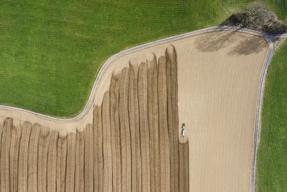 Trecker verteilt auf einem großen Feld Gülle, von oben