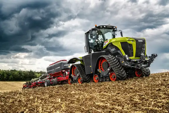 Landmaschine "Raupe" die eine Sähmaschiene zieht, auf einem Feld