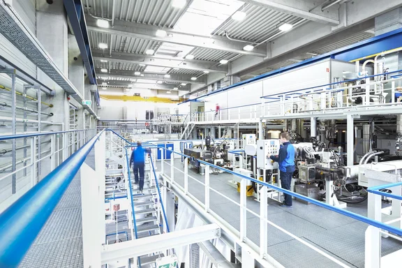 Halle mit Maschinen, an denen Menschen arbeiten, clean