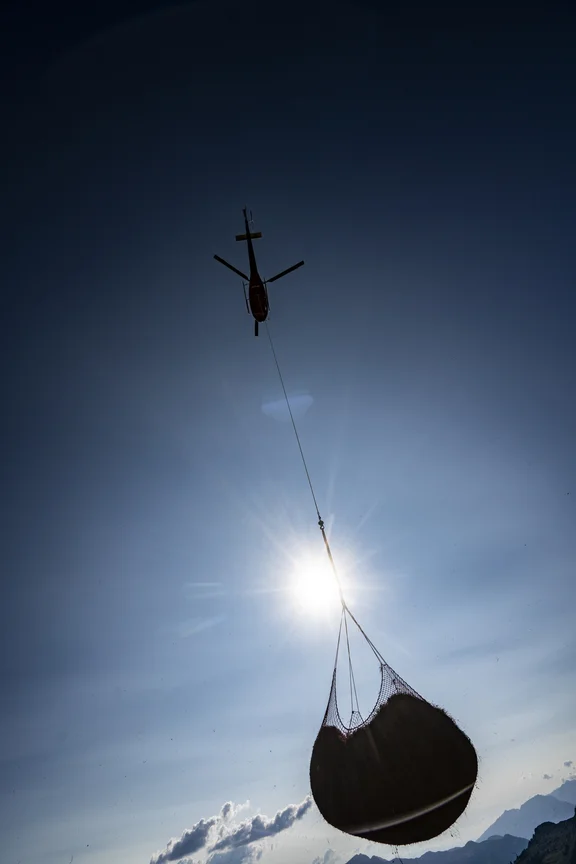 Hubschrauber der ein großes Bündel trägt, Blick von unten in den Himmel