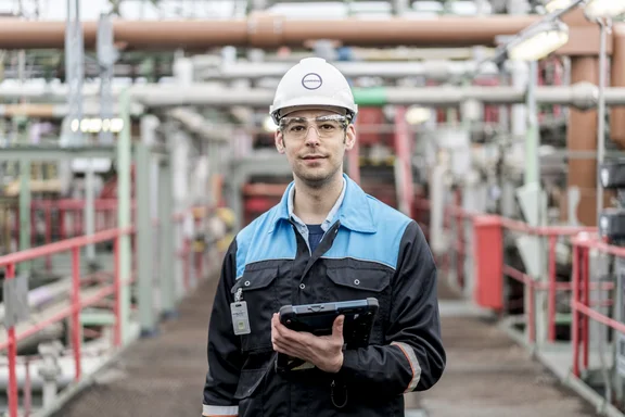 Mann mit Helm auf einer Baustelle, der ein Tablet mit Schutzhülle in der Hand hält