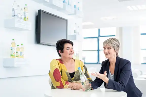 Zwei Frauen unterhalten sich über eine Flasche Gerolsteiner