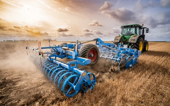 Trecker, der einen blauen Grubber über ein Feld zieht, Blick von hinten