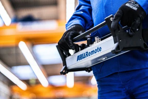 Person in Blauman hat ein Steuergerät von Abus in der Hand, Nahaufname von den Händen