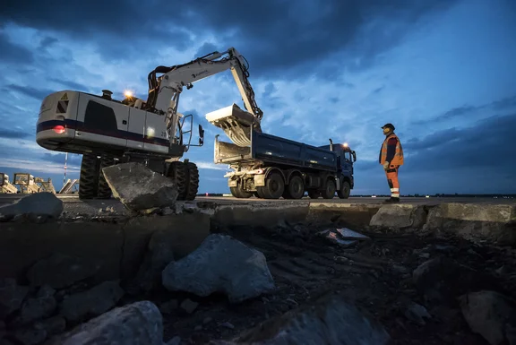 Bagger lädt Betonteile auf einen Lkw spät am Abend