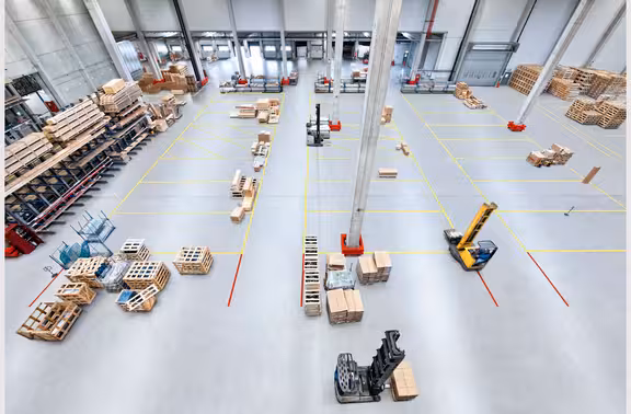 Halle mit Felder auf dem Boden in denen Pakete sortiert sind