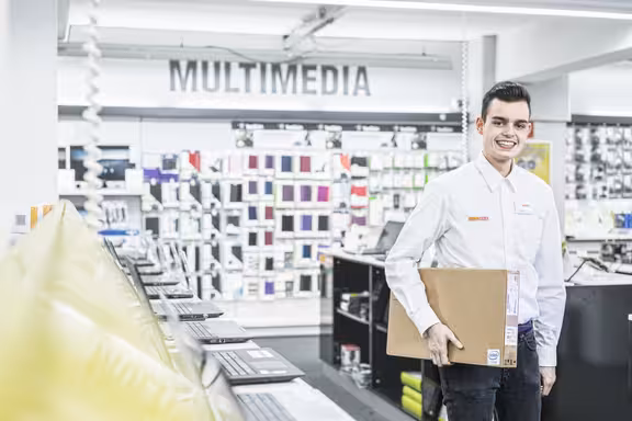 Mann mit Paket unter dem Arm läuft durch einen Gang im Laden
