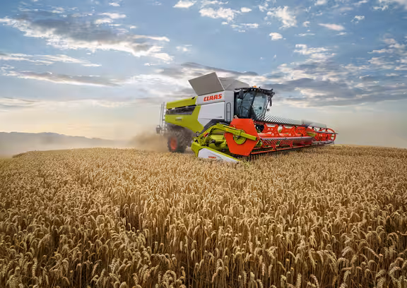 Mähdrescher auf einem Kornfeld, wolkiger Himmel