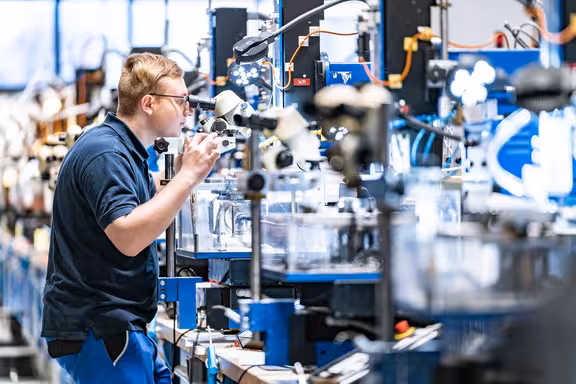 Mann, der durch ein Mikroskop etwas zusammen baut