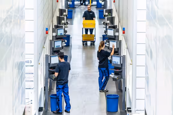 Personen stehen an Computern und bedienen Maschinen