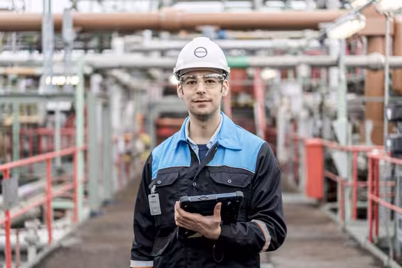 Mann mit Helm auf einer Baustelle, der ein Tablet mit Schutzhülle in der Hand hält