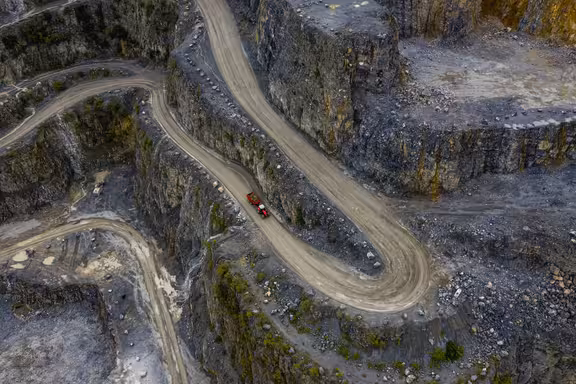 Trecker mit Anhänger fährt auf einem Weg an einem Steinbruch