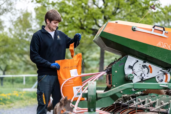 Mann, der einen Samensack auf einer Sähmaschine öffnet