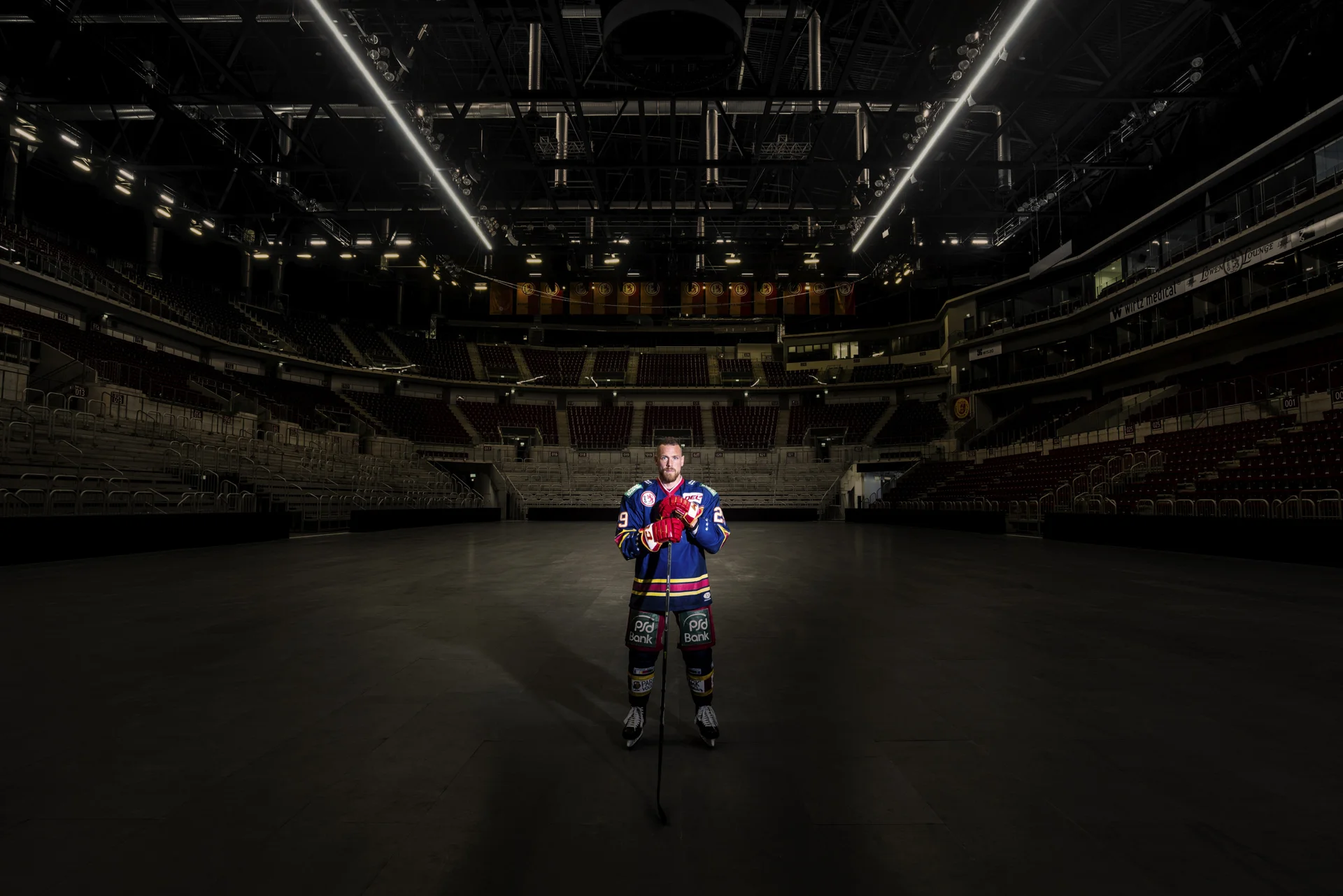 Lichtspot auf Hockyspieler in der Mitte einer leeren Eishalle