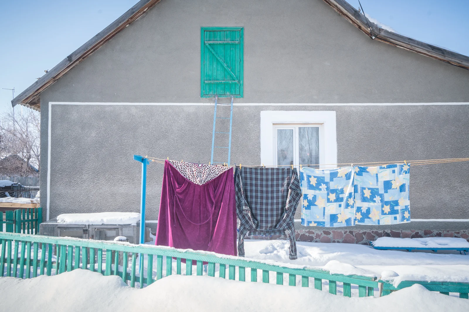 Bunte Wäsche auf einer Wäscheleine vor einem grauen Haus