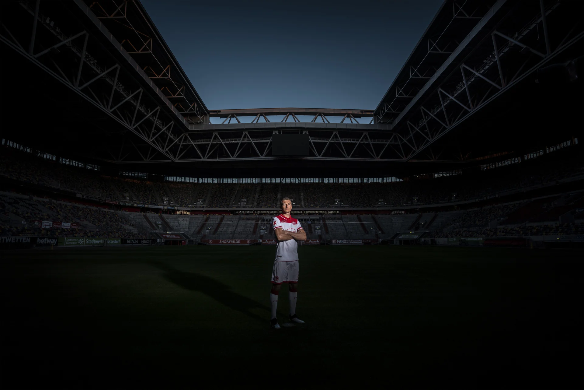 Fußballspieler mit Lichtspot in der Mitte eines leeren Stadions