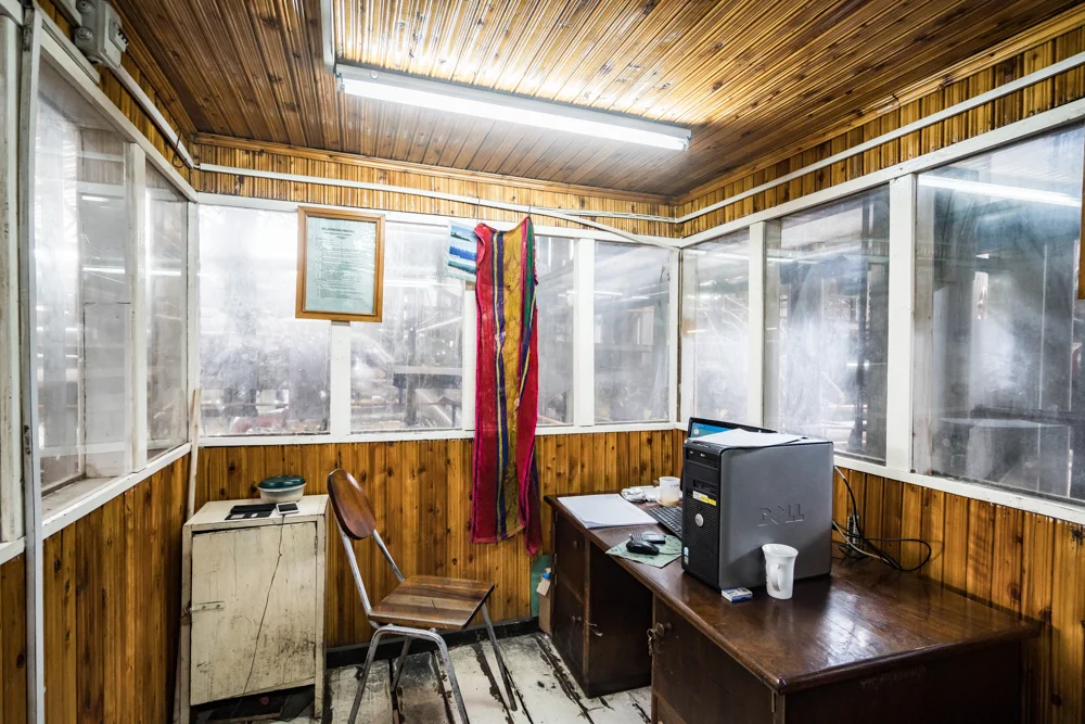 Schreibtisch mit Computer auf dem Tisch und Stuhl in einem mit Holz vertäfelten Raum mit Fensterfront